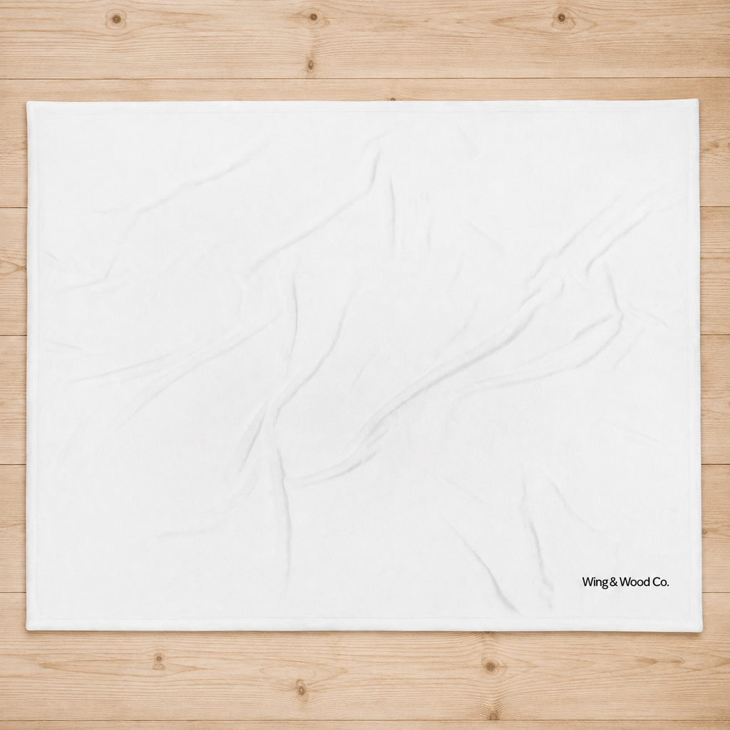 A large white fabric backdrop sheet with subtle wrinkles, laid flat on a light-colored wooden plank background. The brand name 'Wing & Wood Co.