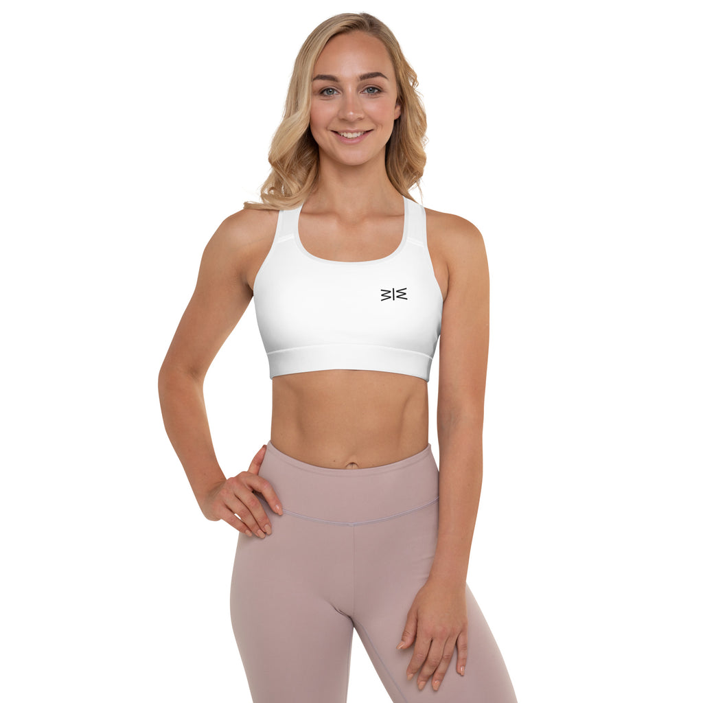 A woman modeling a white sports bra and light pink leggings against a solid white background.