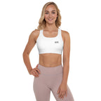 A woman modeling a white sports bra and light pink leggings against a solid white background.