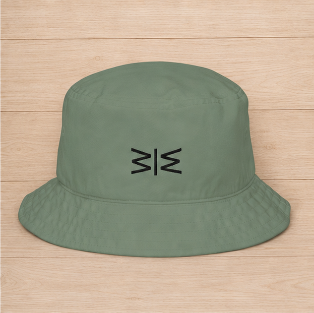An olive green bucket hat with a black embroidered geometric logo on the front, displayed flat on a light wood plank background.