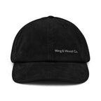 A black corduroy baseball cap with 'Wing & Wood Co.' embroidered in white on the front, shown against a plain white background.