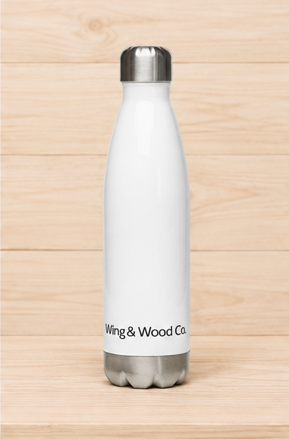 A white insulated water bottle with a silver metal cap and base, featuring the text 'Wing & Wood Co.' printed in black near the bottom, set against a light wood plank background.