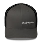 A dark gray trucker cap with black mesh back panels and white embroidered text reading 'Wing & Wood Co.' on the front, shown against a plain white background.