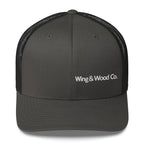 A dark gray trucker hat with black mesh back panels and white embroidered text reading 'Wing & Wood Co.' on the front, shown against a plain white background.