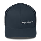 A dark navy blue trucker hat with a structured front panel and curved brim, featuring white embroidered text reading 'Wing & Wood Co.' on the front, set against a plain white background.