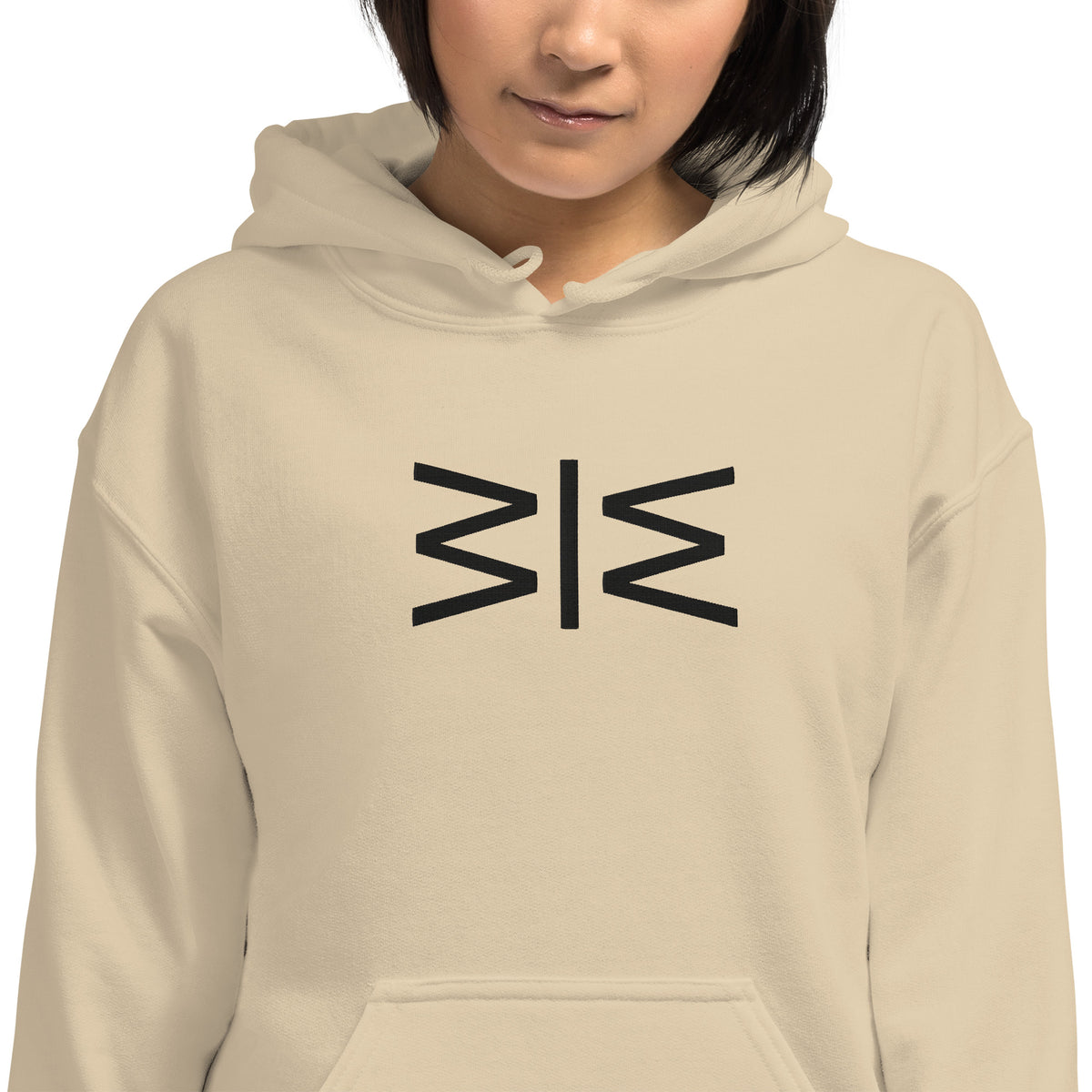 A person wearing a light beige hoodie with a black geometric symbol printed on the chest, shown against a plain white background.