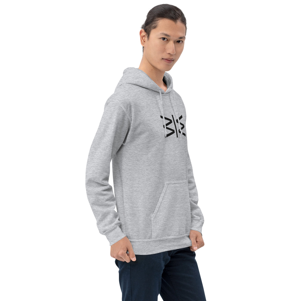 A man wearing a light gray heather pullover hoodie with a black stylized graphic on the chest, paired with dark blue jeans, photographed against a solid white background.