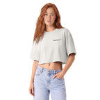 A woman with long red hair wearing a light gray heather cropped t-shirt with 'wing & wood co.' printed in black on the chest, paired with light blue jeans, against a plain white background.